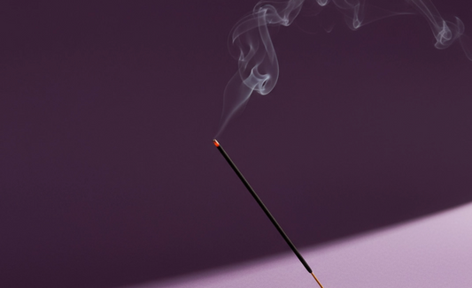 Incense stick with smoke against a dark background