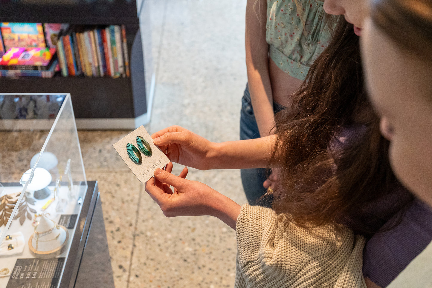 Image of Museum Guest Holding Oval String Earrings/ Light Blue and Greens.