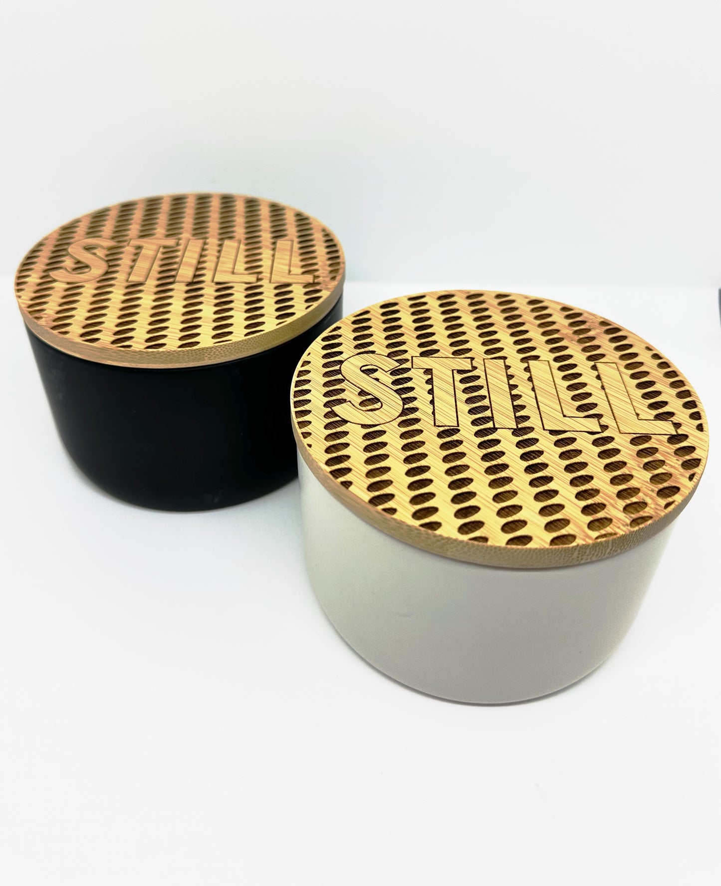 Two variations of the STILL Ceiling Candle. Black or White ceramic and topped with a Museum ceiling inspired laser-engraved bamboo lid. 