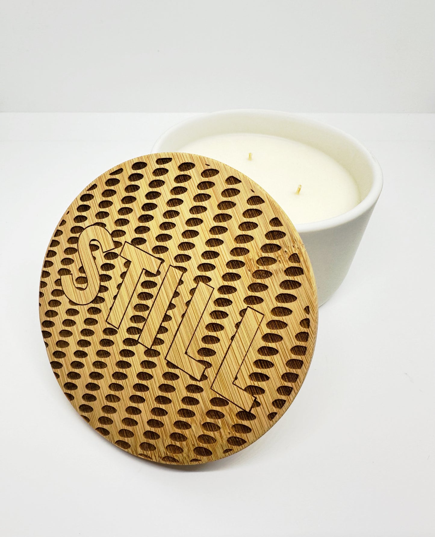 Large candle in white ceramic and topped with a Museum ceiling inspired laser-engraved bamboo lid. 
