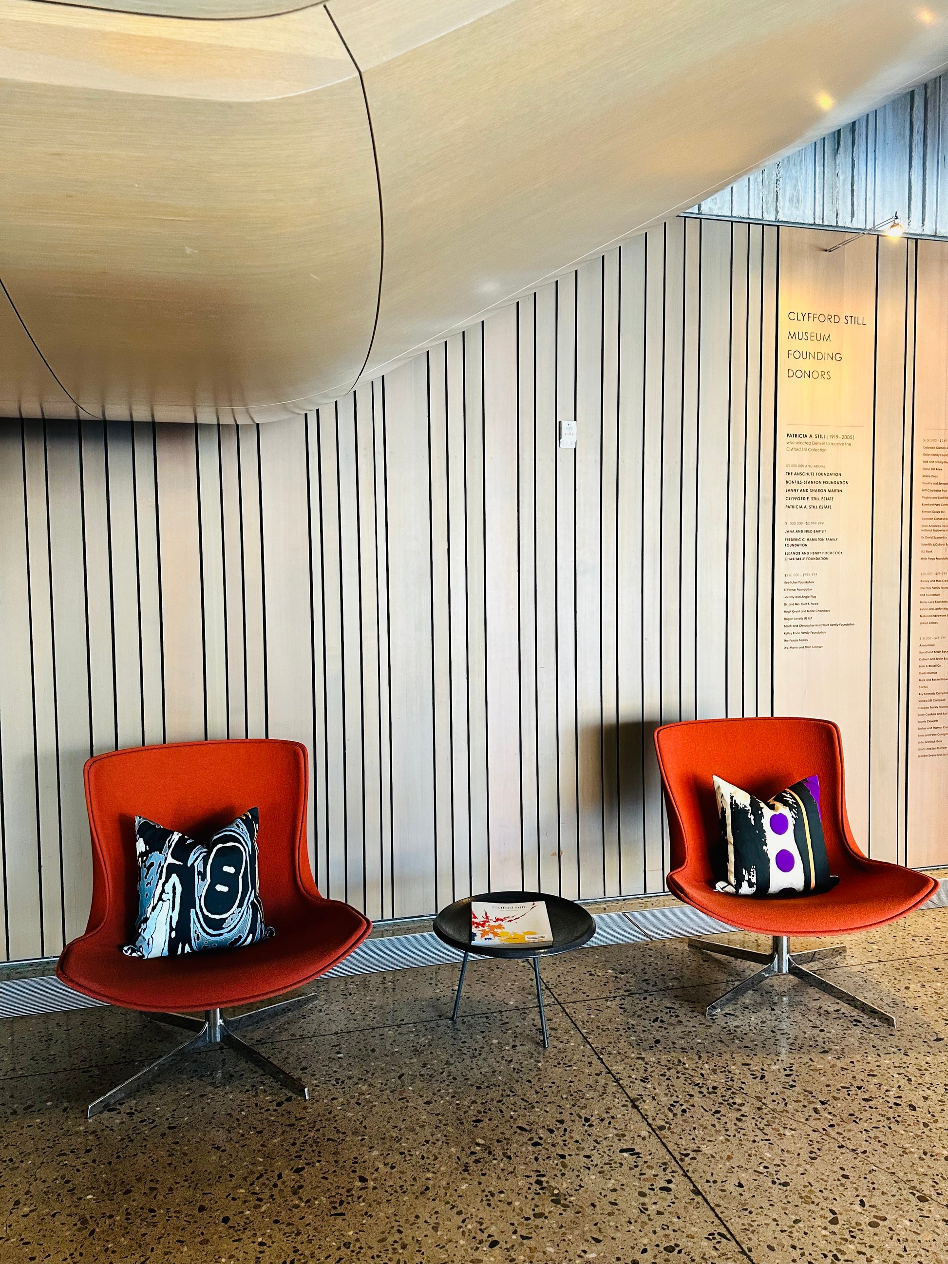Photo of museum lobby chairs each with a Abstract pillow cover.
