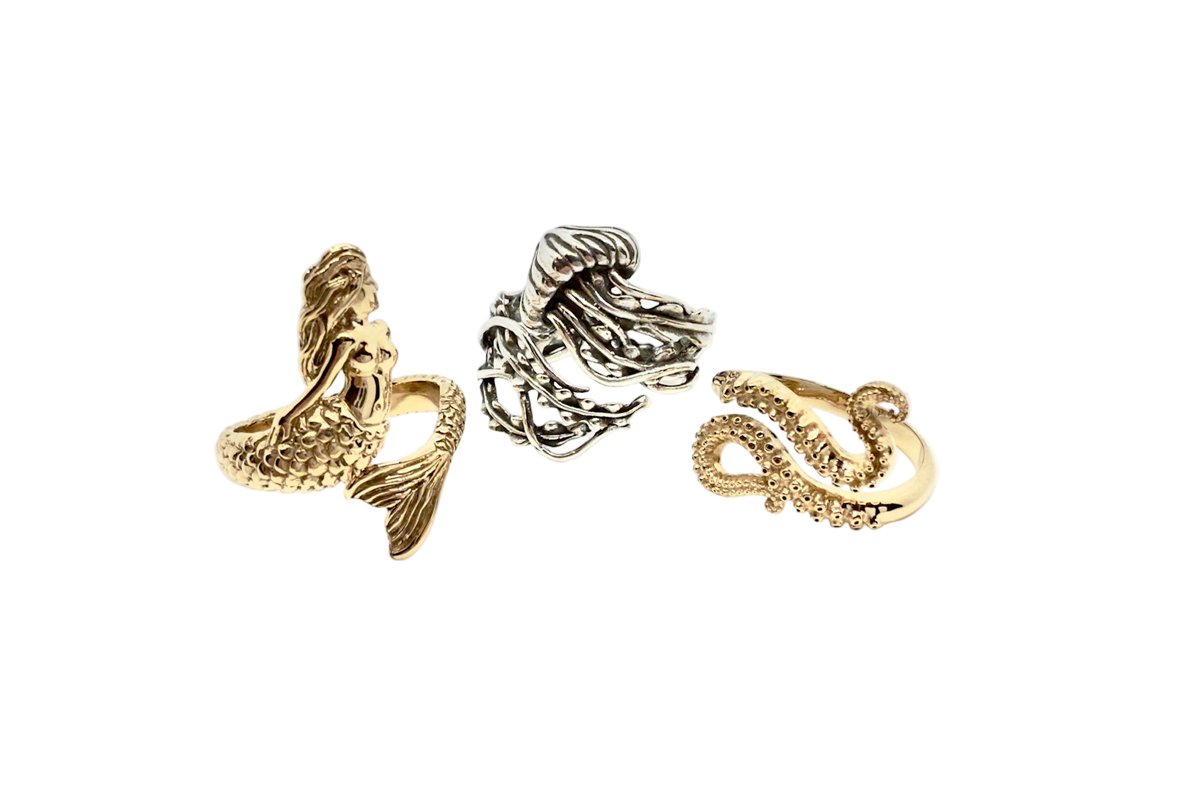 A gold mermaid-shaped ring, a bronze jellyfish-shaped ring, and a gold octopus tentacle-shaped ring 