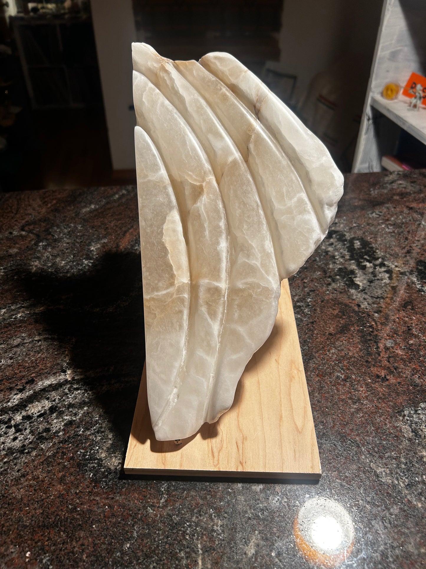 Decorative alabaster sculpture on a wooden base with a dark countertop background