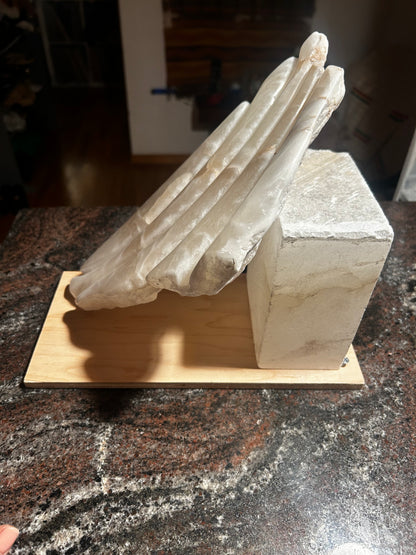 Alabaster sculpture on a wooden base on a dark surface