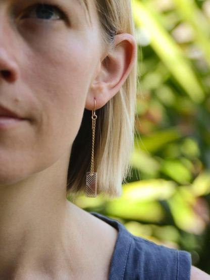 Photo of a woman wearing Osa/Oda Earring. Transparent handpainted acrylic rectangle, dangling from gold-fill {g} Rolo chain.
