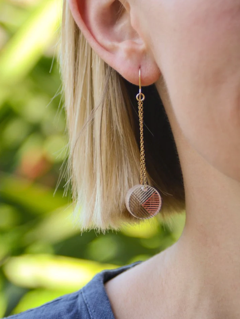 Photo of a woman wearing Osa/Oda Earring. Transparent handpainted acrylic circle, dangling from gold-fill {g} Rolo chain.

