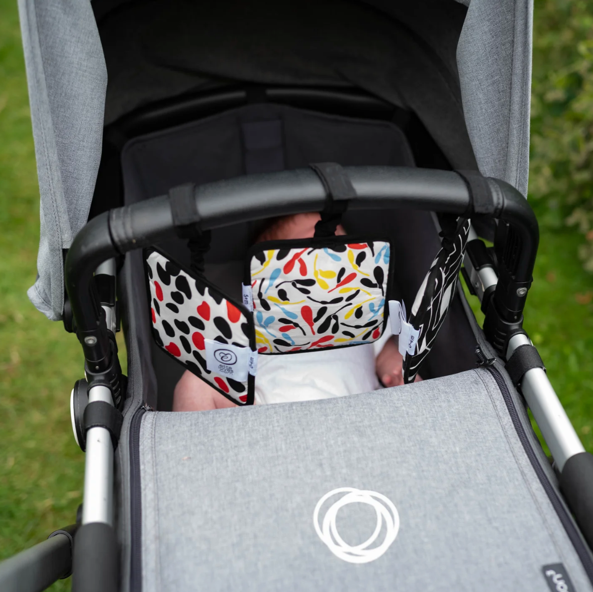 Photo showing baby in baby stroller looking at sensory hanging squares.