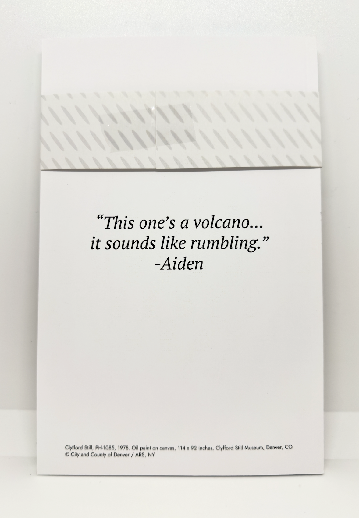 White notebook with black quote text on the back saying "This one's a volcano... it sounds like rumbling."