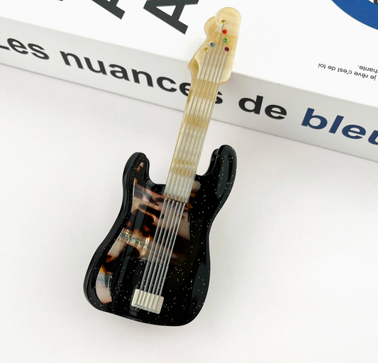 Guitar-shaped hair clip on a magazine page
