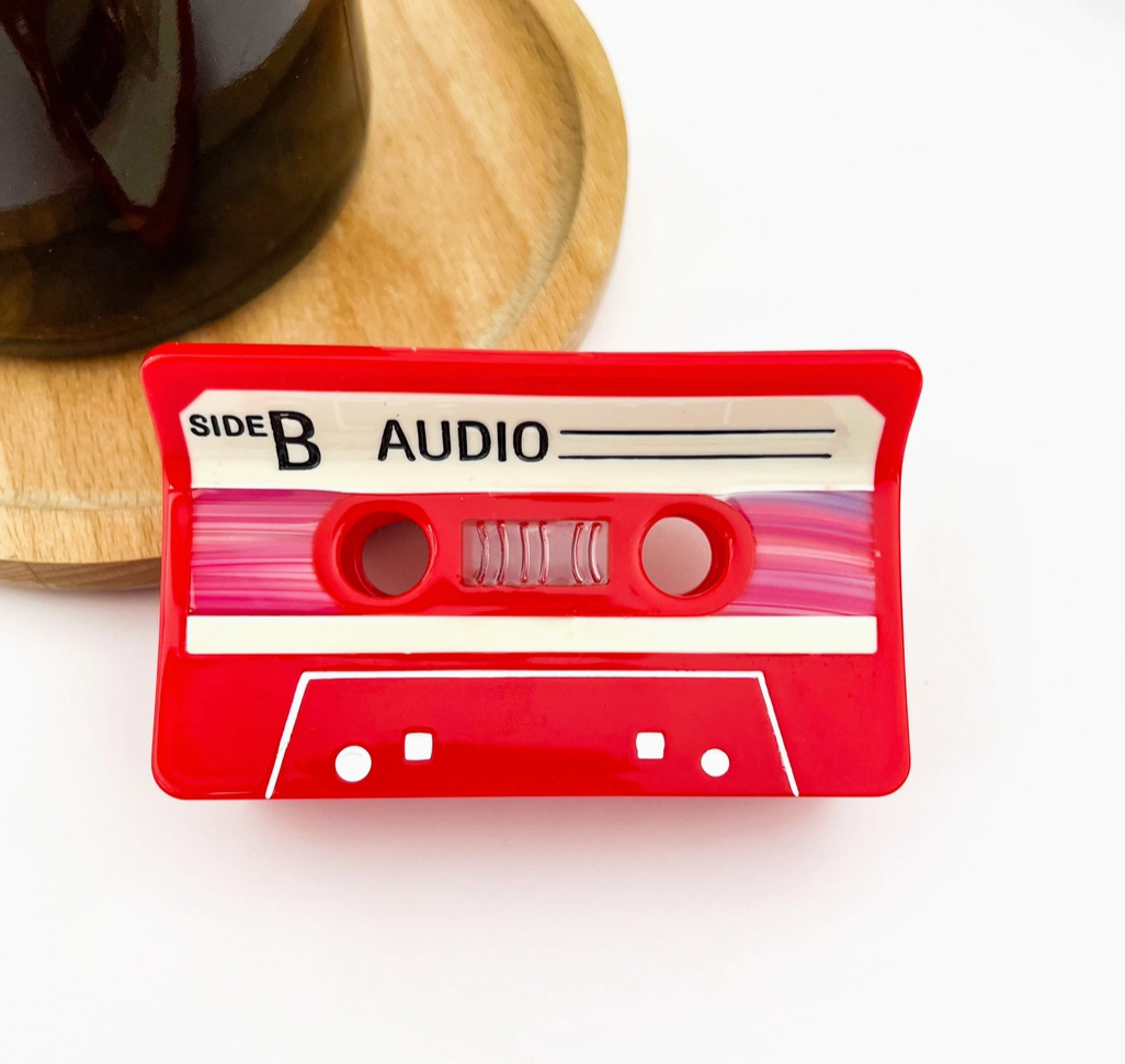 Red audio cassette tape hair clip with 'Side B Audio' label on a white background.