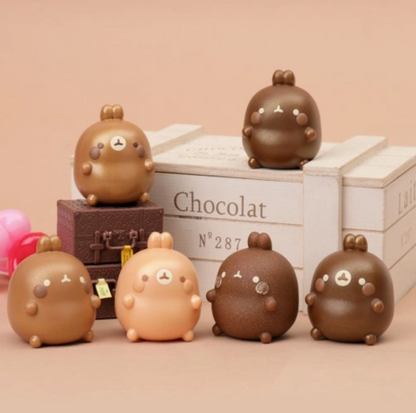 Set of cute chocolate-like figurines with a 'Chocolat' box in the background.