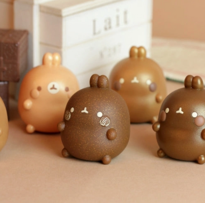 Cute chocolate-like figurines with faces on a beige surface.