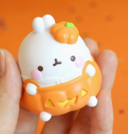 Cute Halloween-themed figurine held in a hand against an orange background