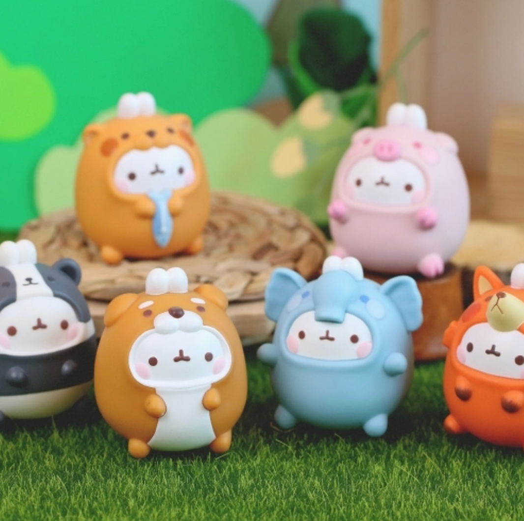 Set of cute animal figurines on a grassy surface with a blurred green background