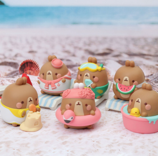 Set of cute brown animal figurines on a beach with ocean in the background