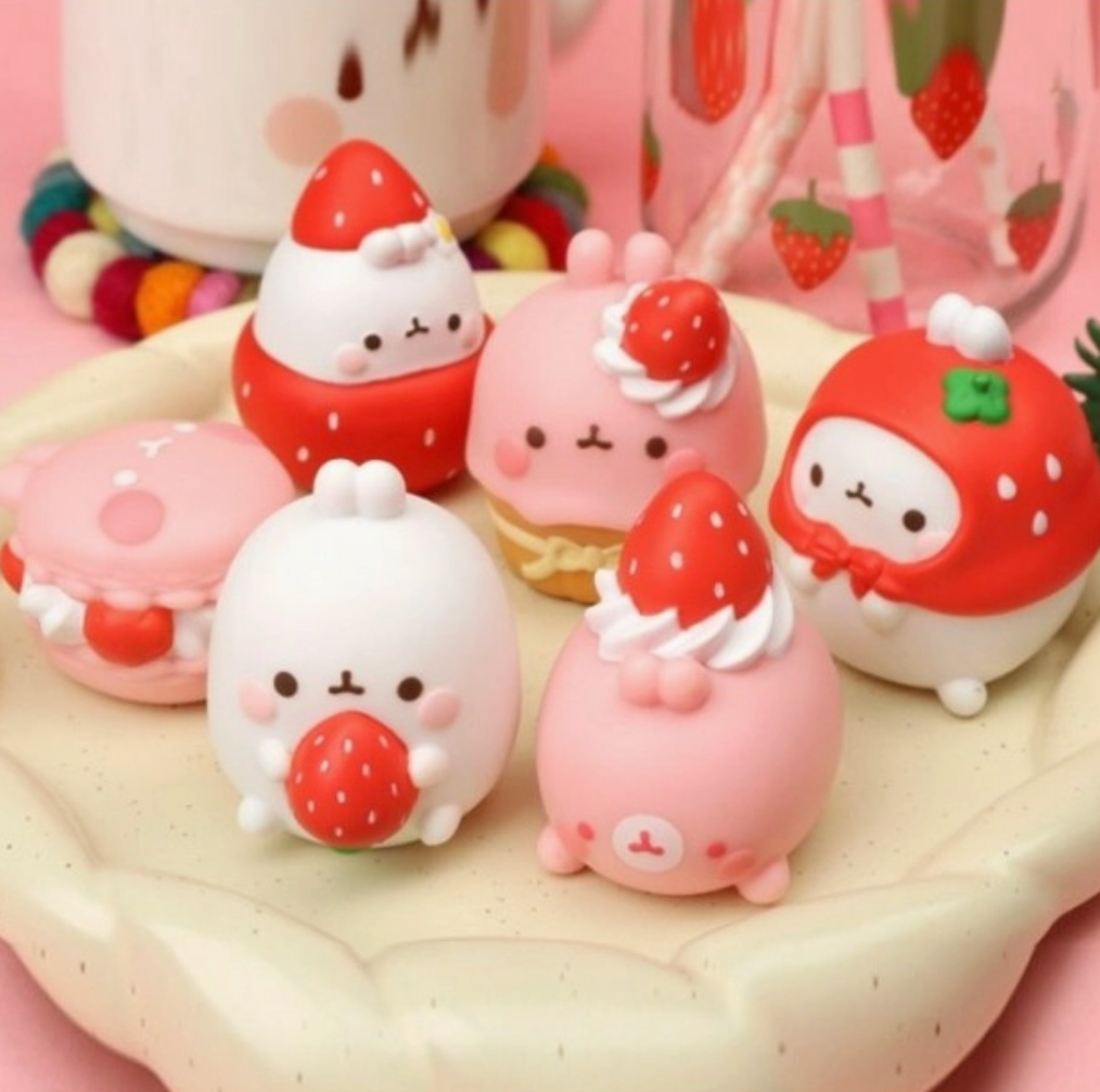 Set of cute strawberry-themed figurines on a pink background