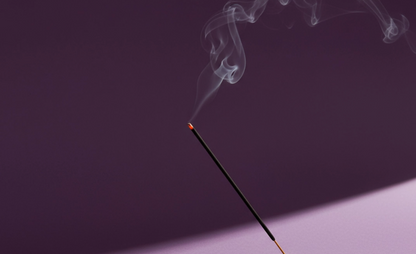 Incense stick with smoke against a dark background