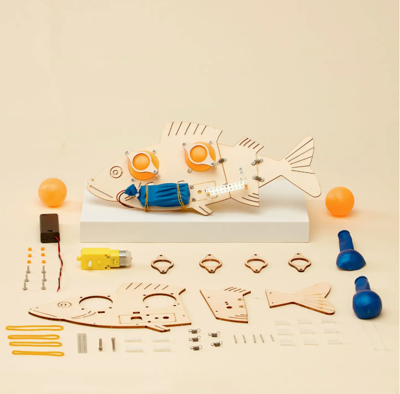 Wooden fish-shaped kit with components on a beige background