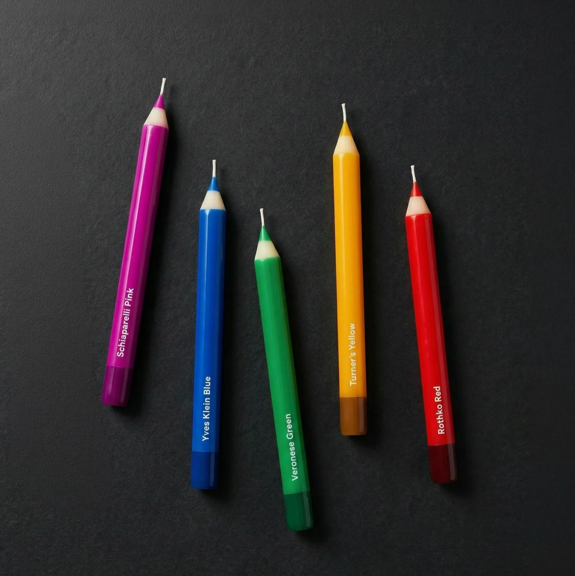 Five colored pencil candles on a black background