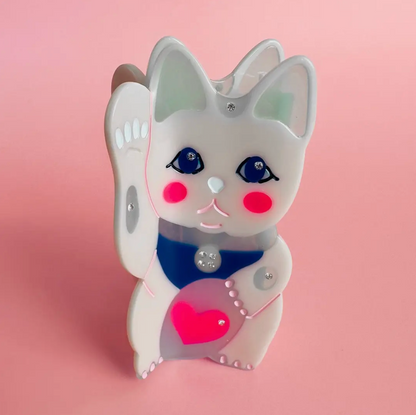 Cute cartoon-style lucky cat hair clip with a pink heart on a pink background