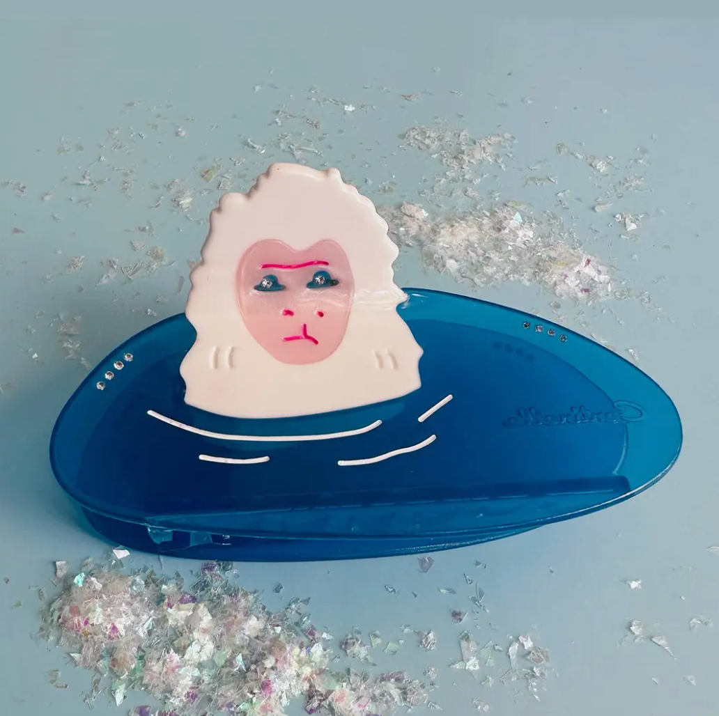 Snow monkey in a blue water with glittery confetti on a light blue background