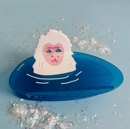 Snow monkey in a blue water with glittery confetti on a light blue background