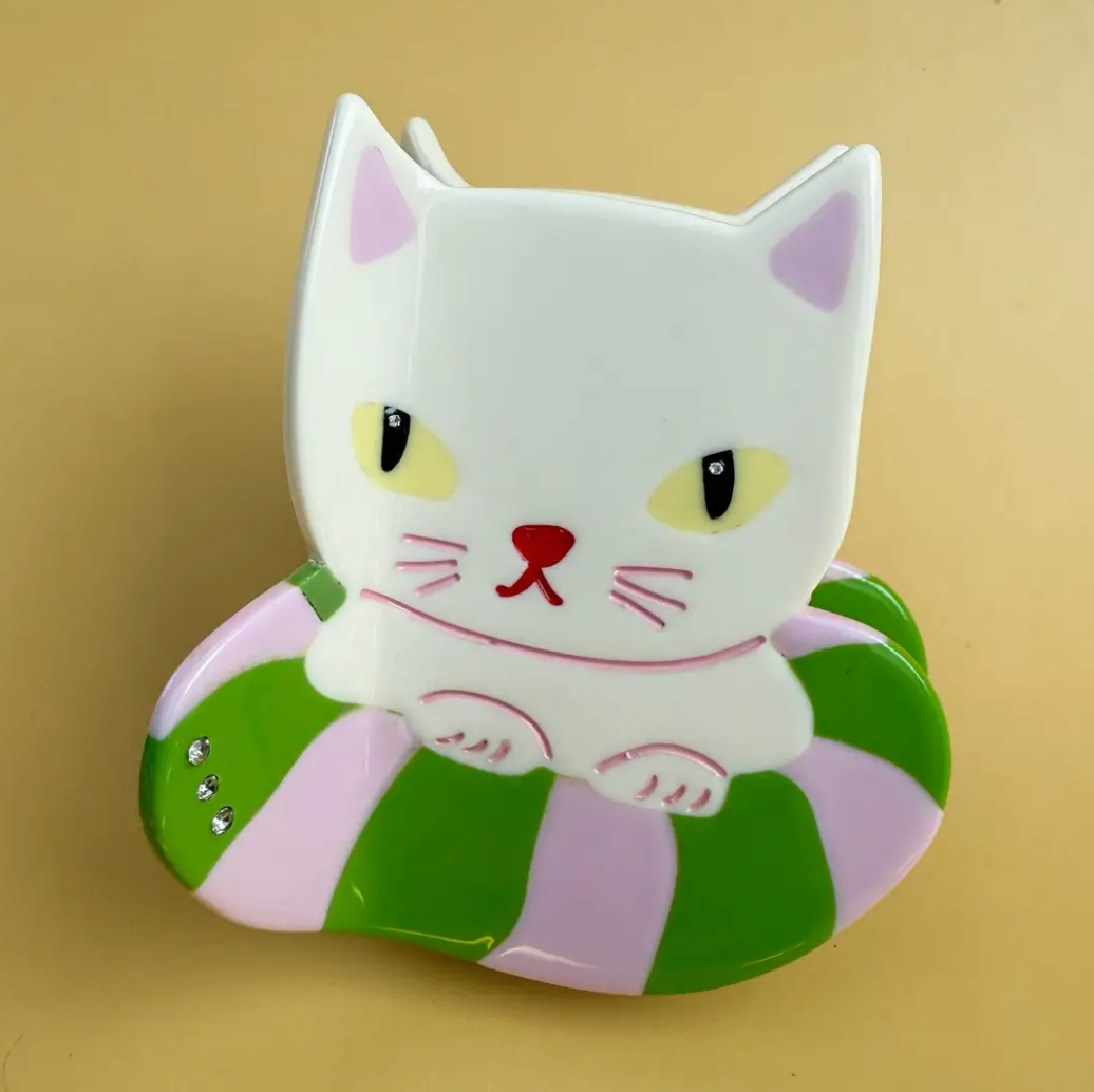 White cat-shaped object with green and purple stripes on a beige background