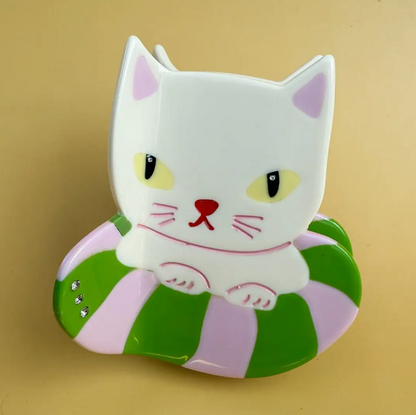 White cat-shaped object with green and purple stripes on a beige background