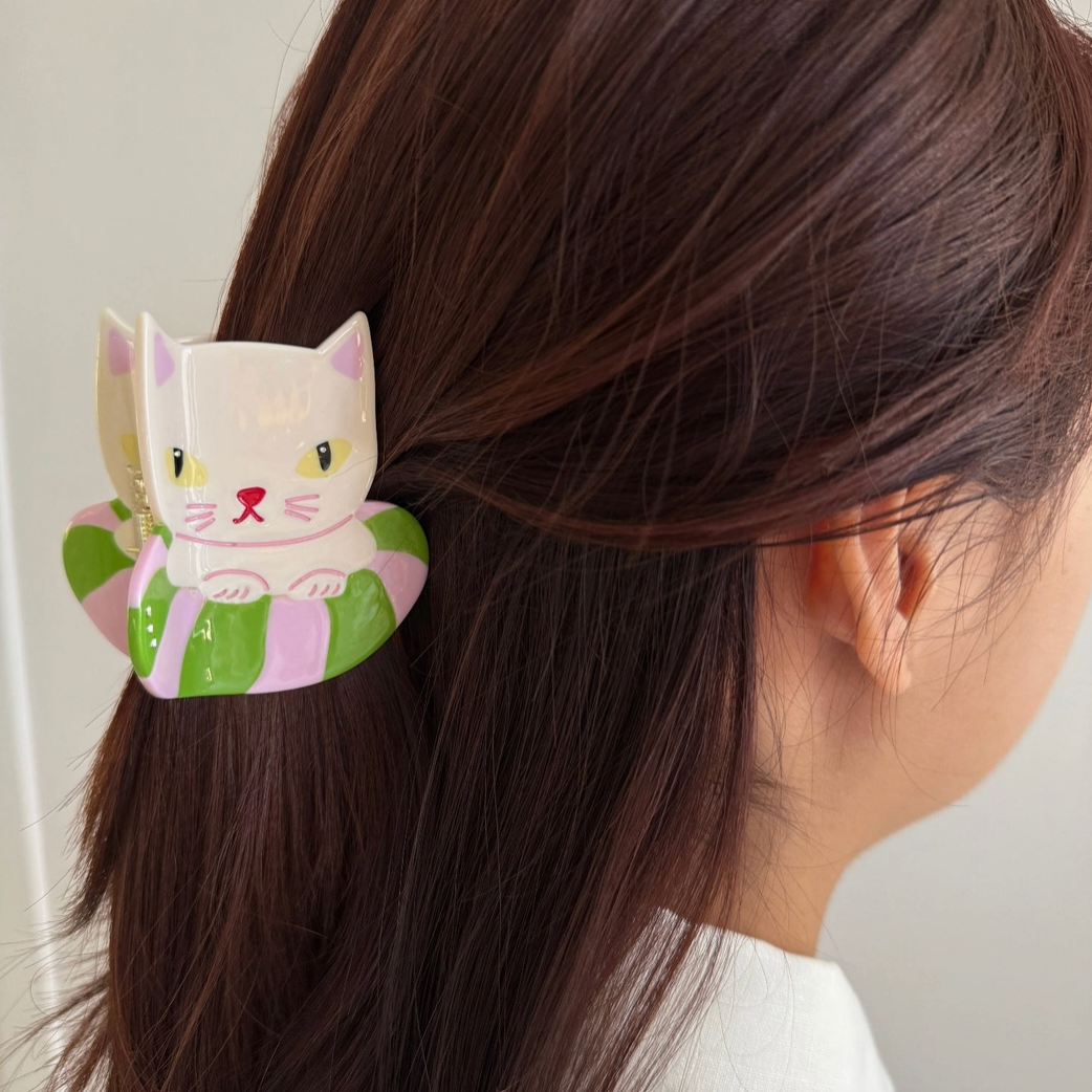 Hair clip with a cat design on a person's hair against a neutral background