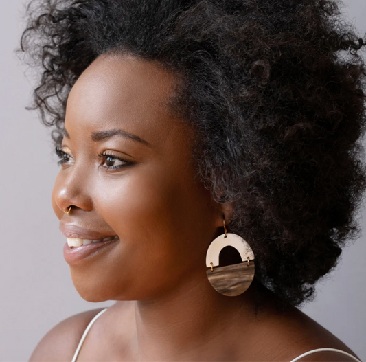 Woman wearing large horn earrings with a neutral background