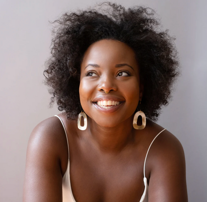 Woman with curly hair wearing hoop earrings against a neutral background