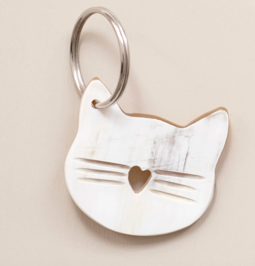 Cat-shaped keychain with a heart detail on a beige background