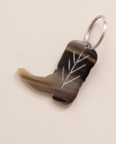 Cowboy boot keychain with engraved design on a beige background