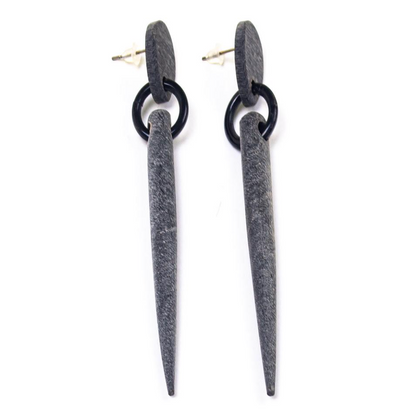 Pair of earrings with black circular top and long gray spike on a white background