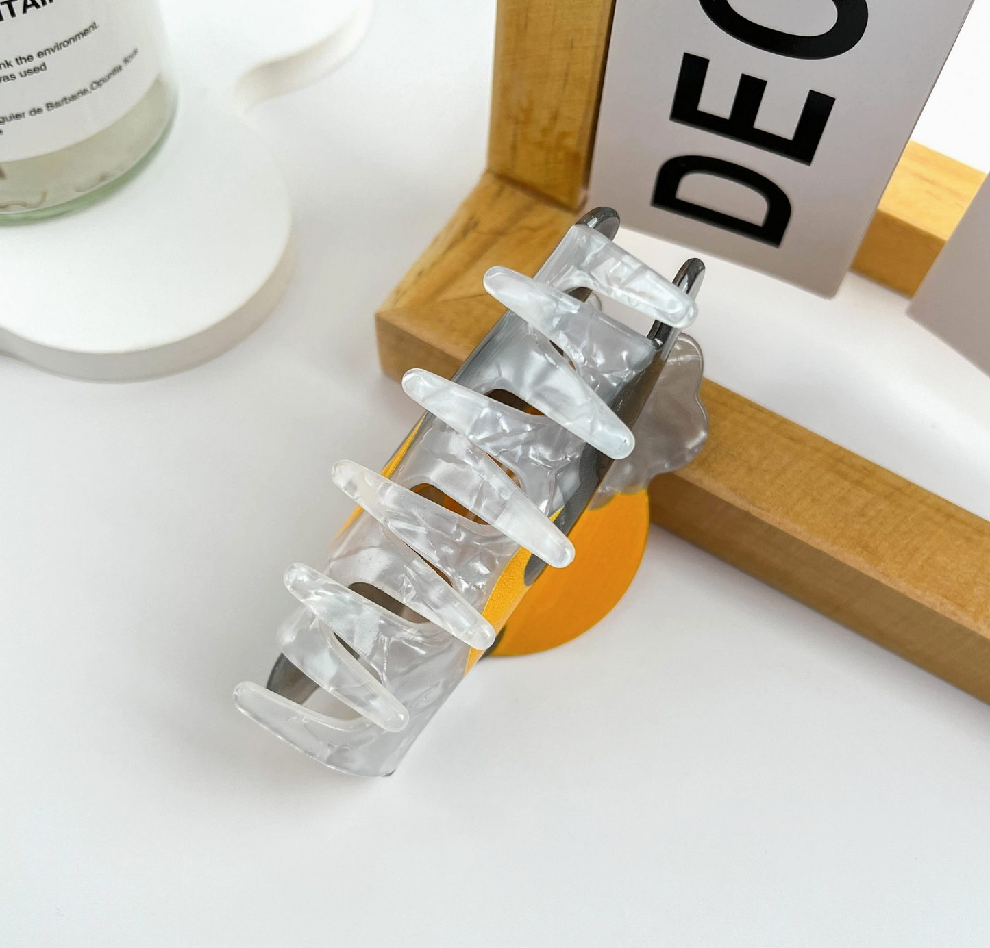 Clear hair clip on a white surface with a wooden frame and text in the background