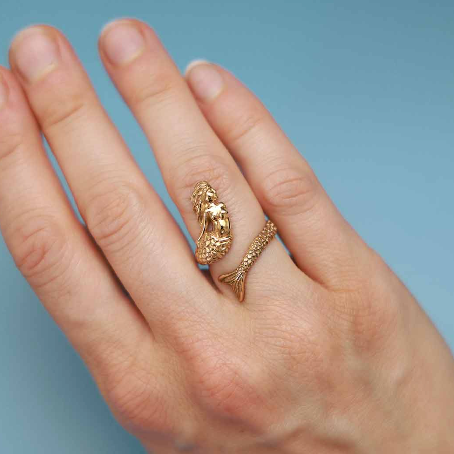 Gold mermaid-shaped ring on finger