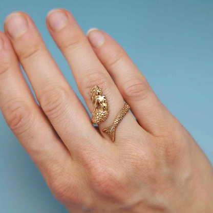 Gold mermaid-shaped ring on finger