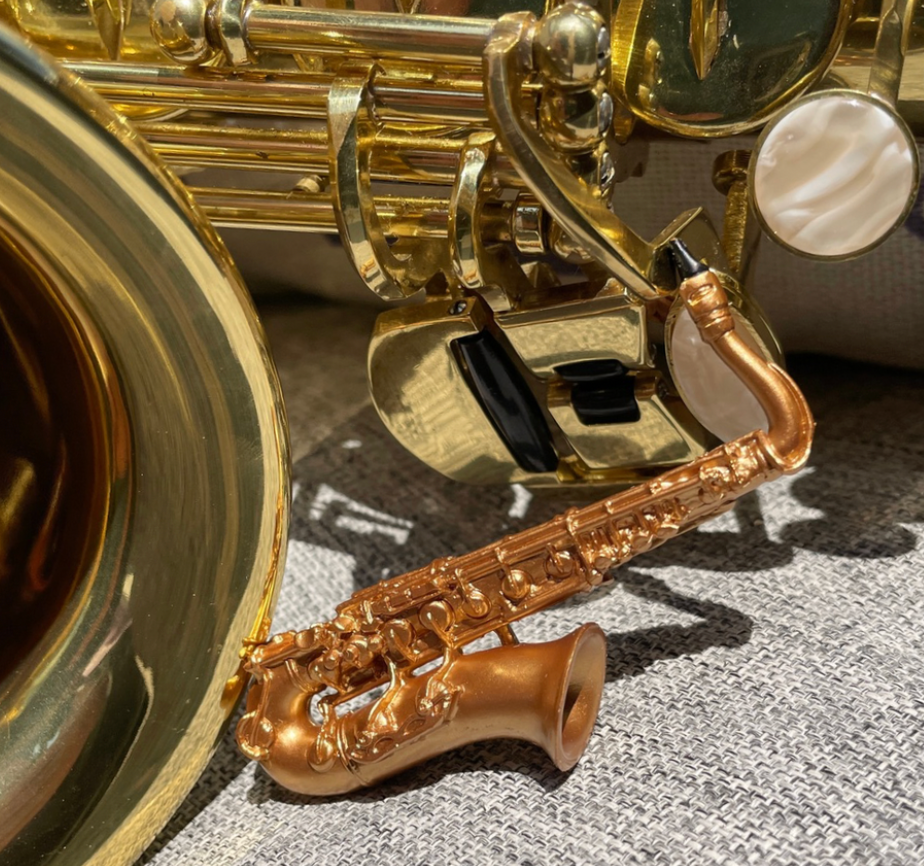 Close-up of a gold saxophone on a textured surface