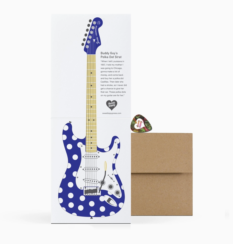 Greeting card with blue and white polka dot guitar design, envelope, and pick on a white background