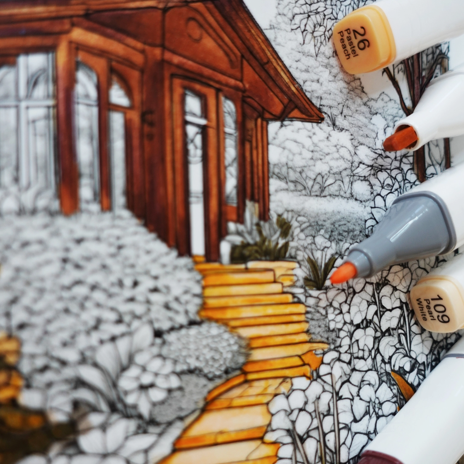 Coloring book page with a wooden cabin illustration and markers.