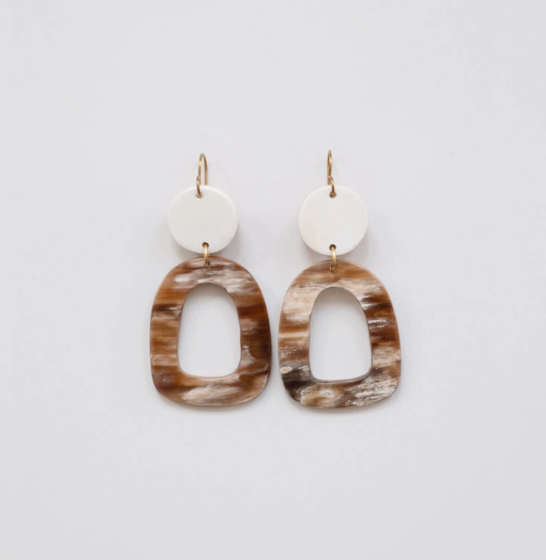 Pair of horn earrings with brown and beige oval shapes on a light gray background