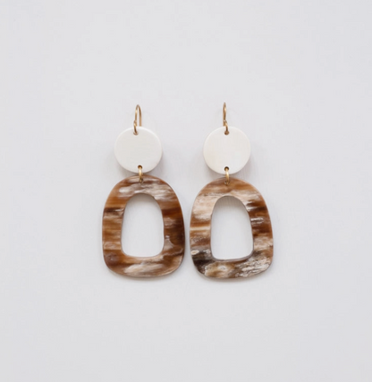 Pair of horn earrings with brown and beige oval shapes on a light gray background