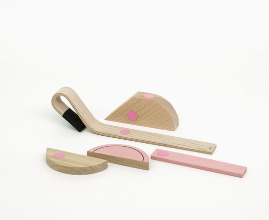 A set of minimalist wooden blocks and rods with pink circular accents, arranged on a clean white background.