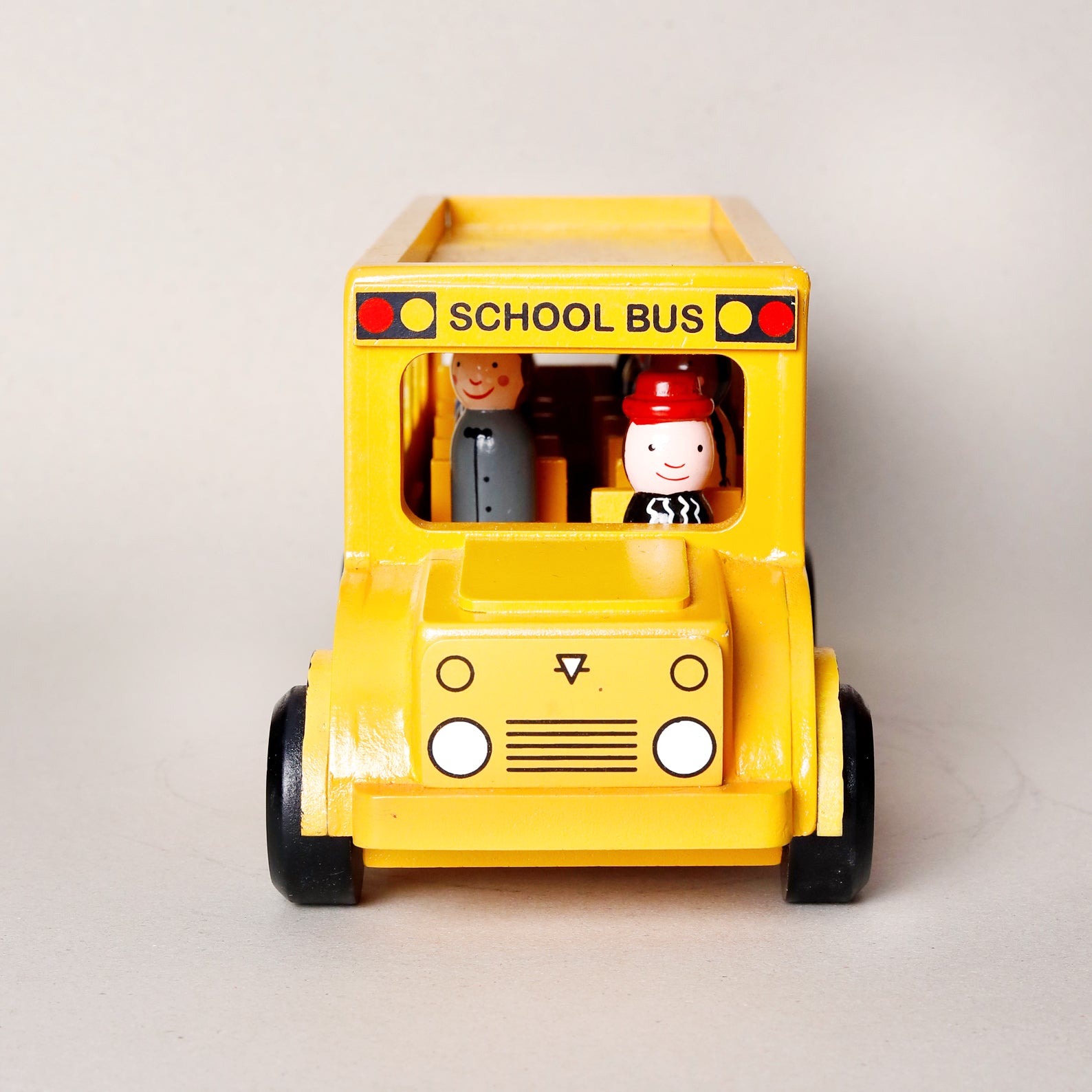 Toy school bus with two figures on a light gray background