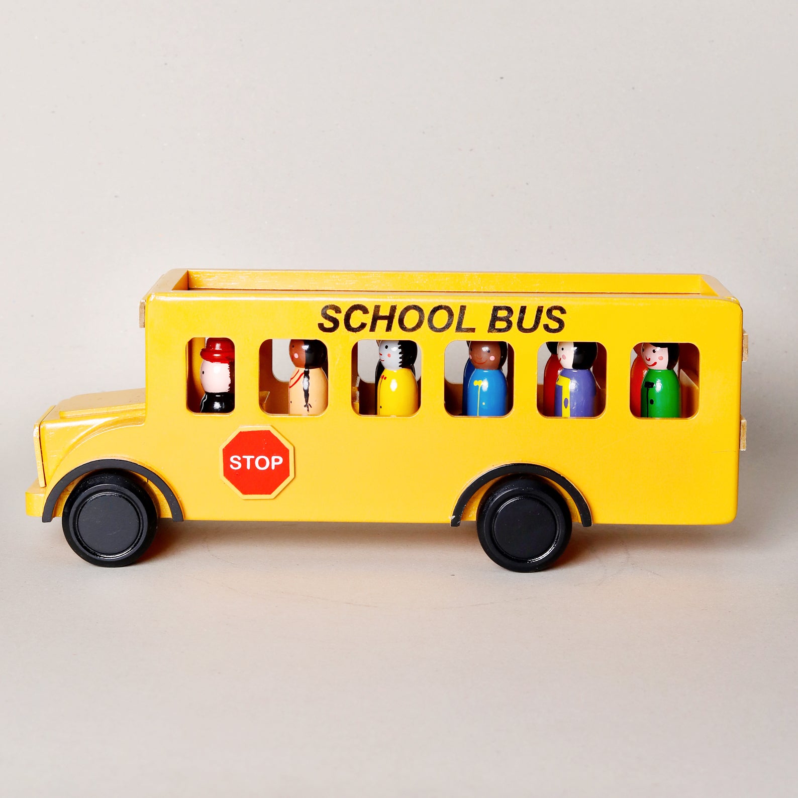 Toy school bus with colorful figures inside on a light gray background