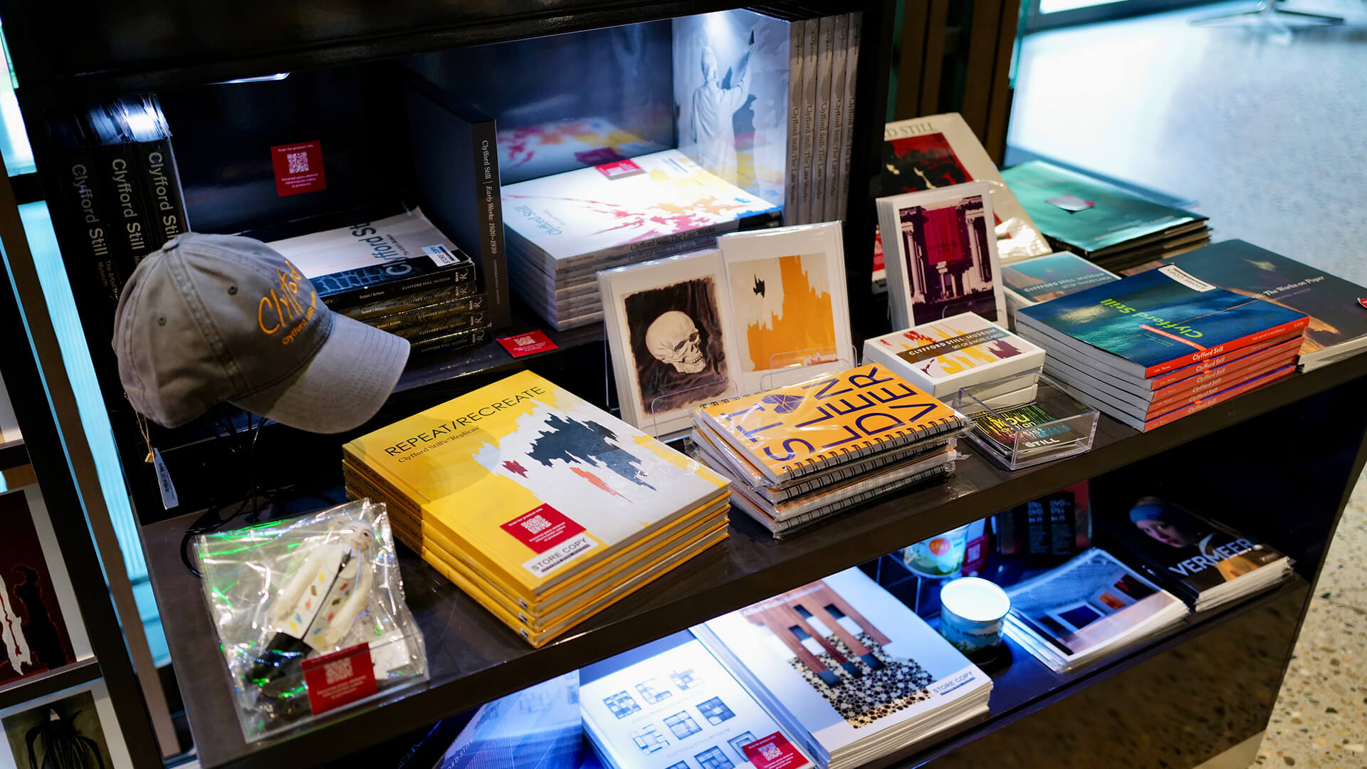 Display of books, magazines, and a cap on a shelf with a blurred background