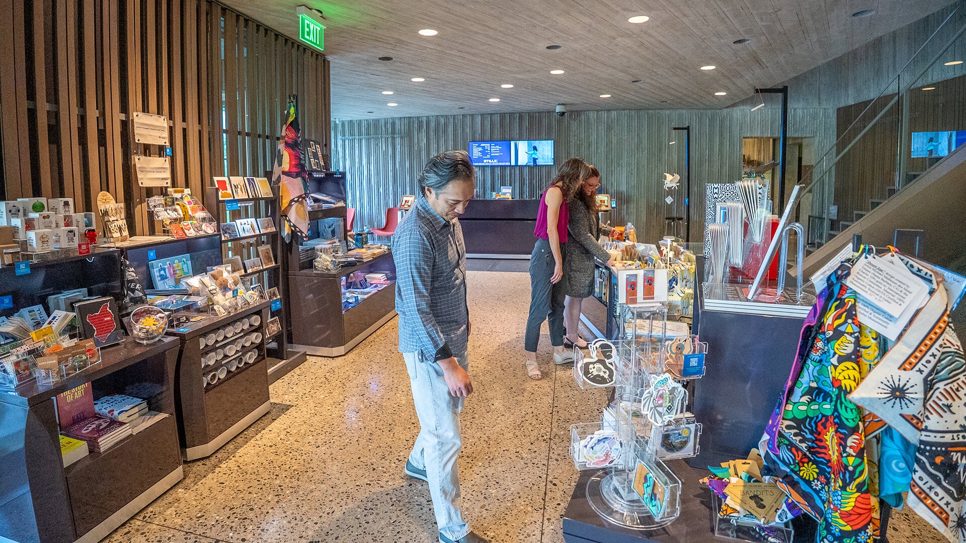 People browsing in a store with various products on shelves and display cases.